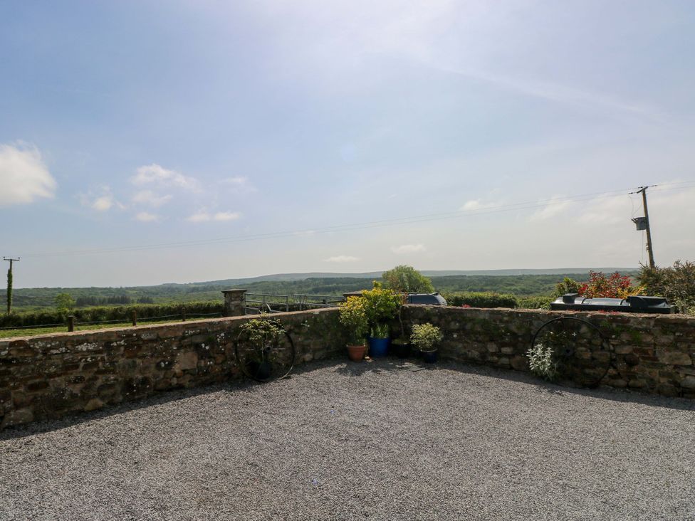 An outdoor space with a stone wall and plant pots at The Stall in Penuel near Llanmorlais