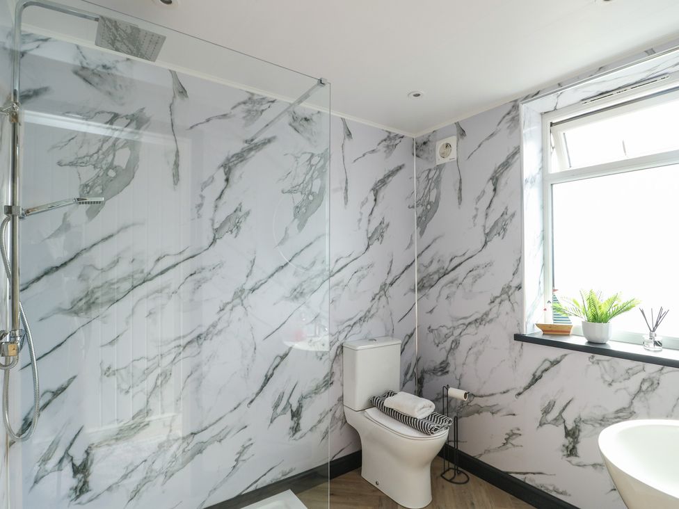A bathroom with a shower, toilet, and sink at Minerva, Trearddur Bay