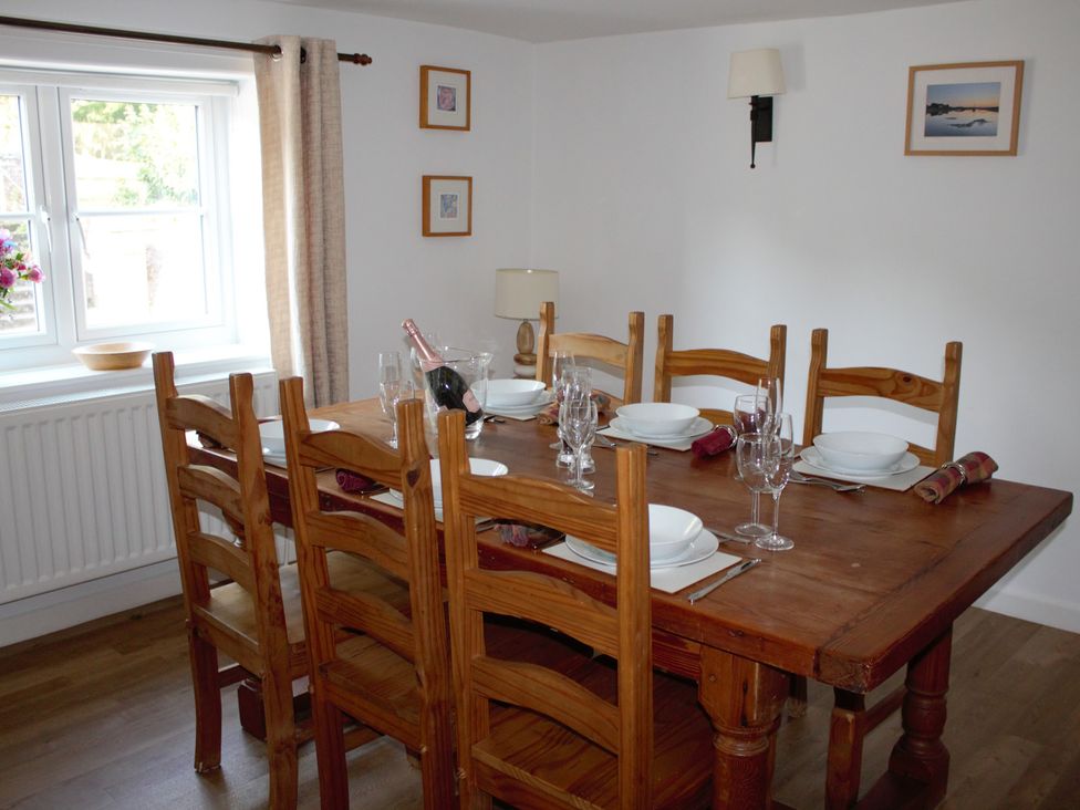 A dining room with a wooden table set for dinner at Manor Farm Cottage Swaffham