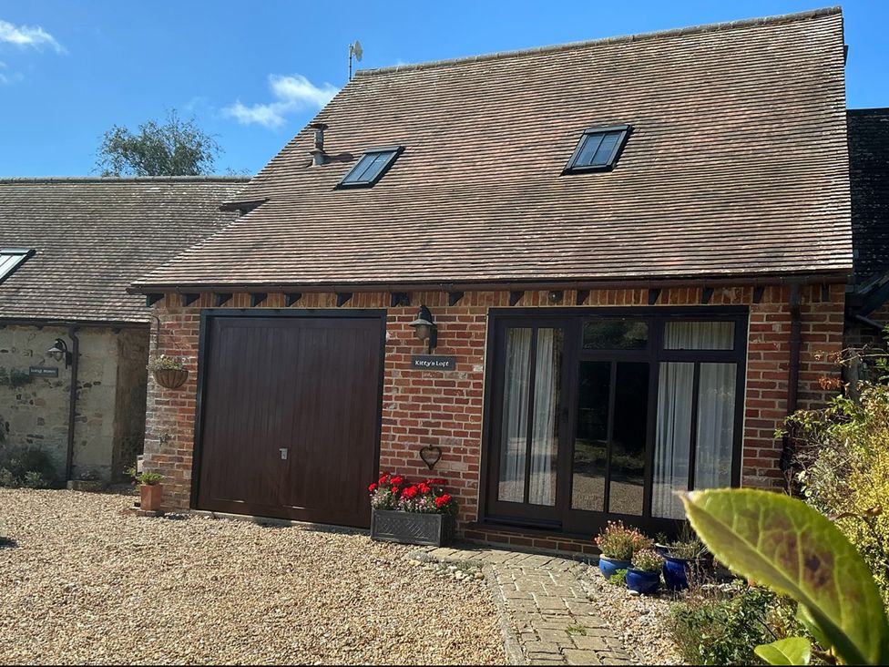 A brick building with windows and flower pots at Kitty's Loft in Great Appleford near Godshill