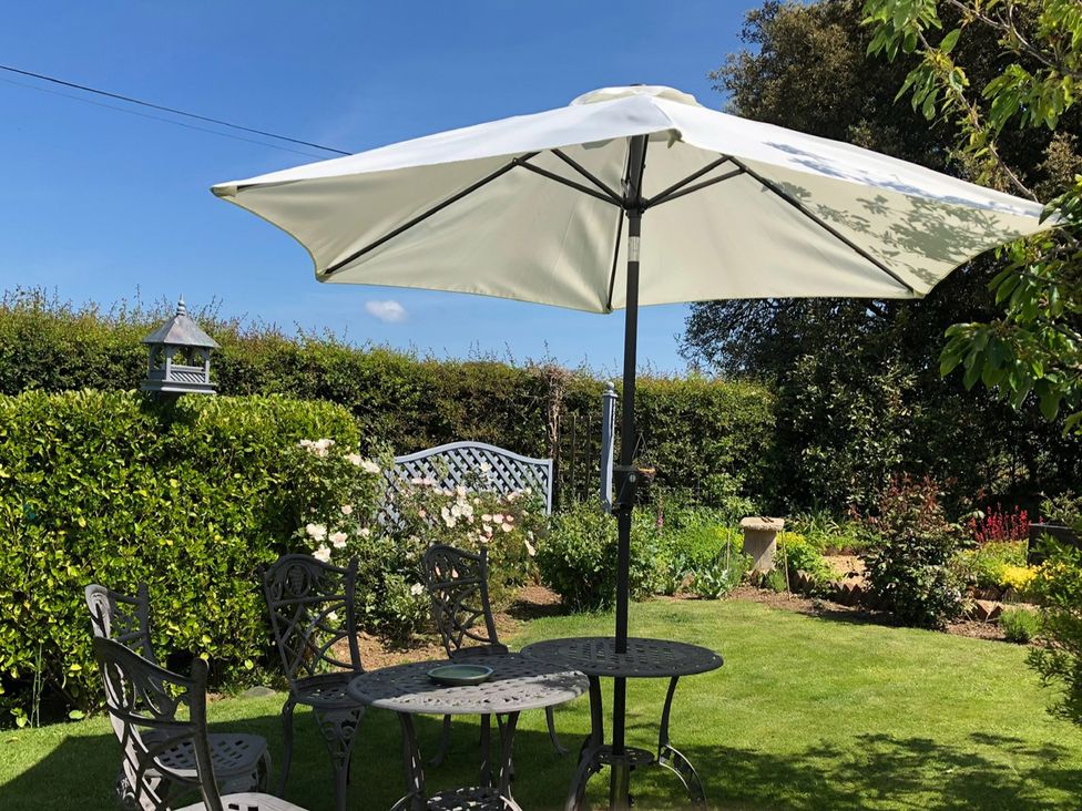 A garden setting with a table and chairs under an umbrella at Kitty's Loft Great Appleford near Godshill