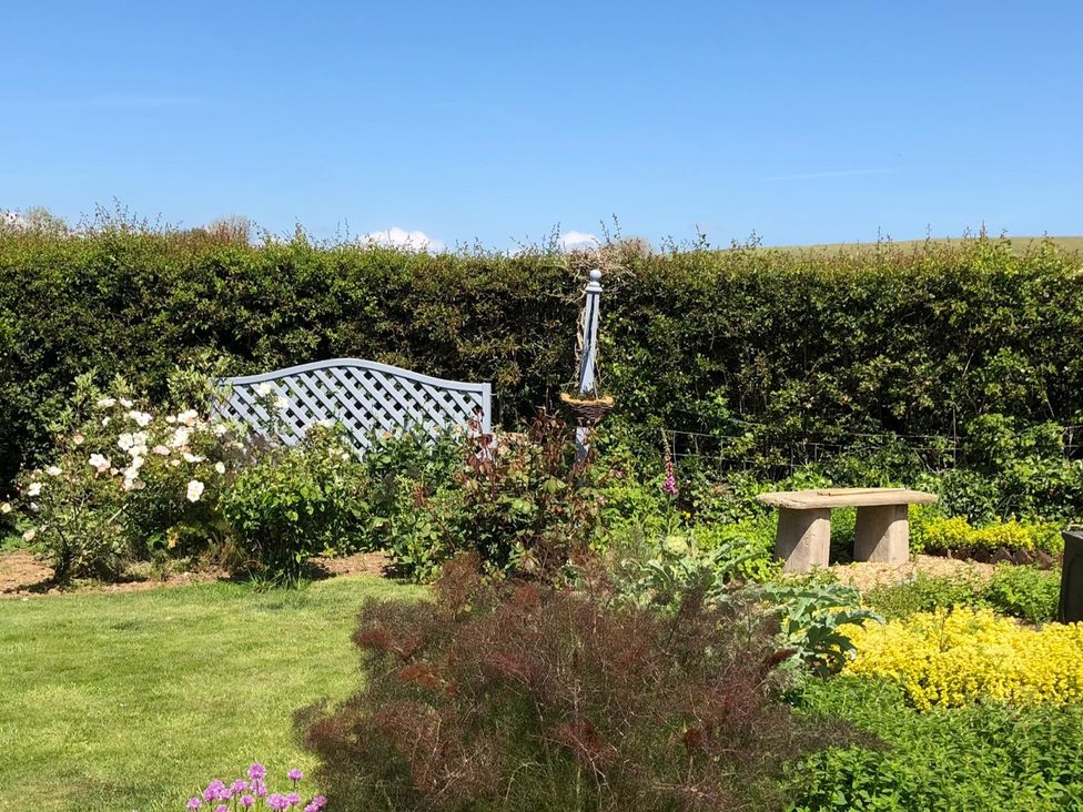 A garden with a blue lattice fence and flowers at Kitty's Loft Great Appleford near Godshill