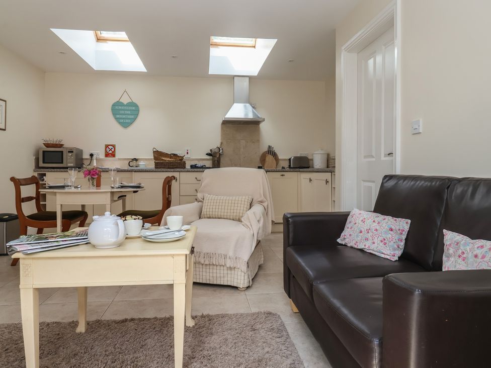 A kitchen with a table, chairs, and a sofa at Stable Cottage in Cawton near Hovingham