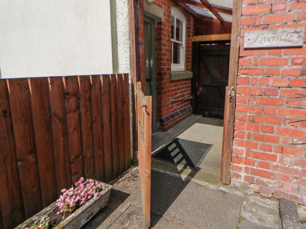 An entrance area with a wooden gate and brick wall at Riverside Cottage Llanwrthwl near Rhayader
