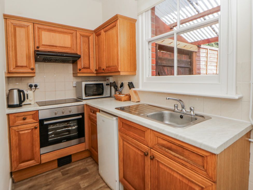 A kitchen with wooden cabinets and appliances at Riverside Cottage Llanwrthwl near Rhayader