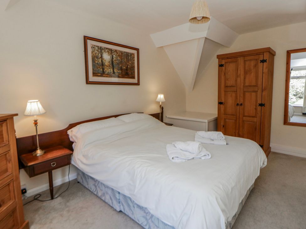 A bedroom with a bed and wardrobe at Riverside Cottage Llanwrthwl near Rhayader