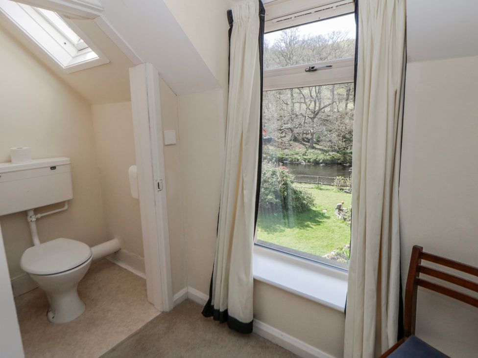 A bathroom with a toilet and window at Riverside Cottage near Llanwrthwl