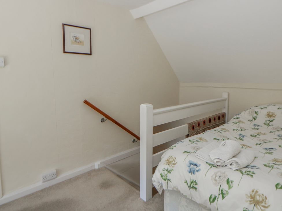 A bedroom with a bed and stairs at Riverside Cottage Llanwrthwl near Rhayader