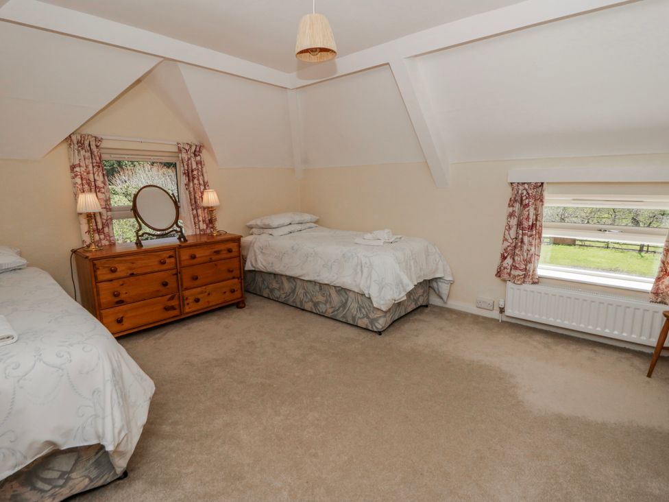 A bedroom with two beds and a dresser at Riverside Cottage Llanwrthwl near Rhayader