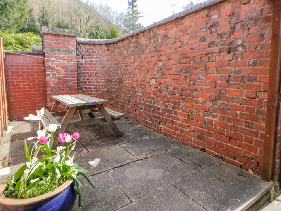 An outdoor area with a wooden table and flowers at Riverside Cottage Llanwrthwl near Rhayader