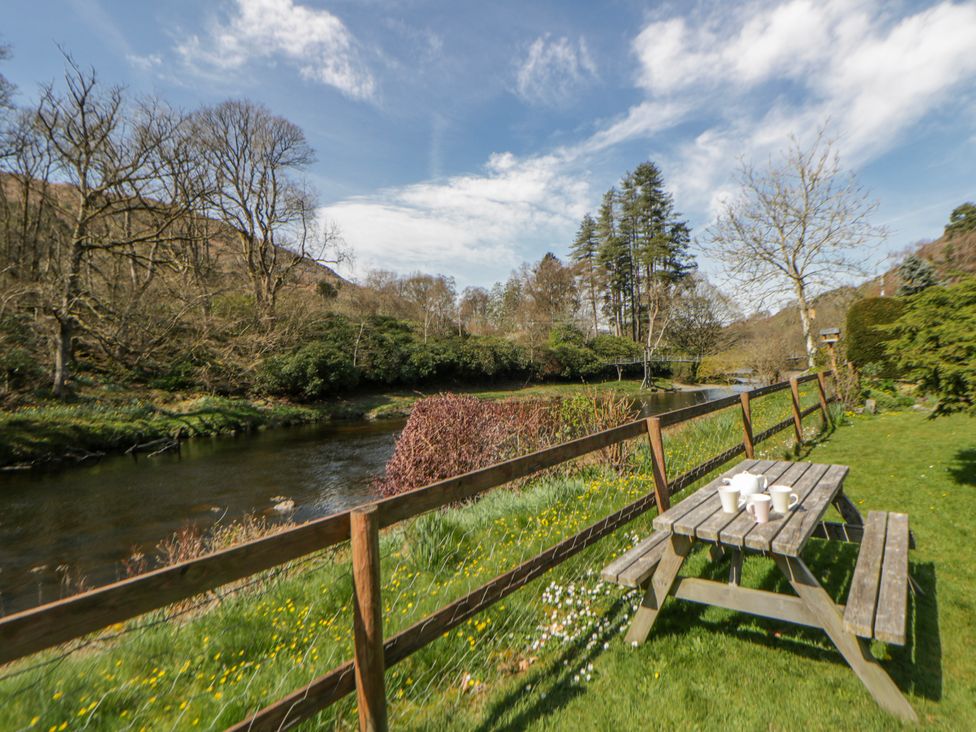 A garden with a table and mugs near a river at Riverside Cottage Llanwrthwl near Rhayader