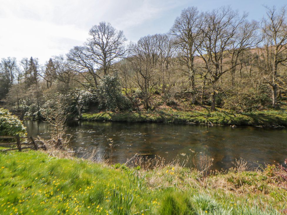 A river with trees and grass at Riverside Cottage Llanwrthwl near Rhayader