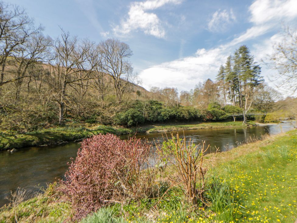 A river with trees and bushes along its banks at Riverside Cottage Llanwrthwl near Rhayader
