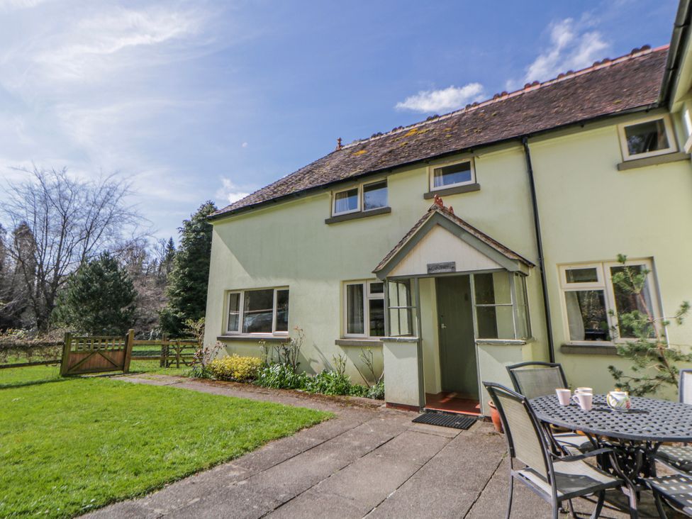 An outdoor area with a house, table, and chairs at Gardener's Cottage in Llanwrthwl near Rhayader