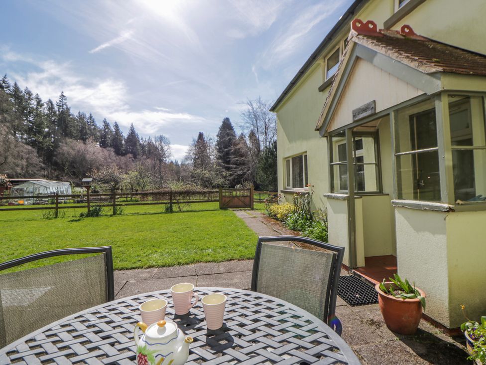 A garden with a table and teapot at Gardener's Cottage in Llanwrthwl near Rhayader