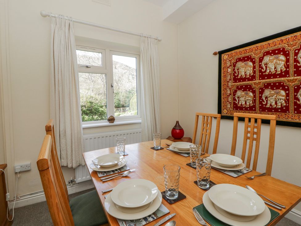 A dining room with a table set for meals at Gardener's Cottage in Llanwrthwl near Rhayader