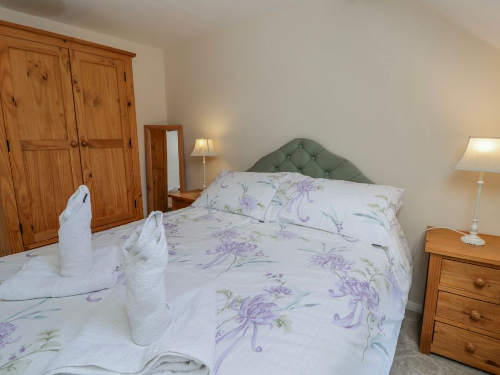 A bedroom with a bed and wardrobe at Gardener's Cottage in Llanwrthwl near Rhayader