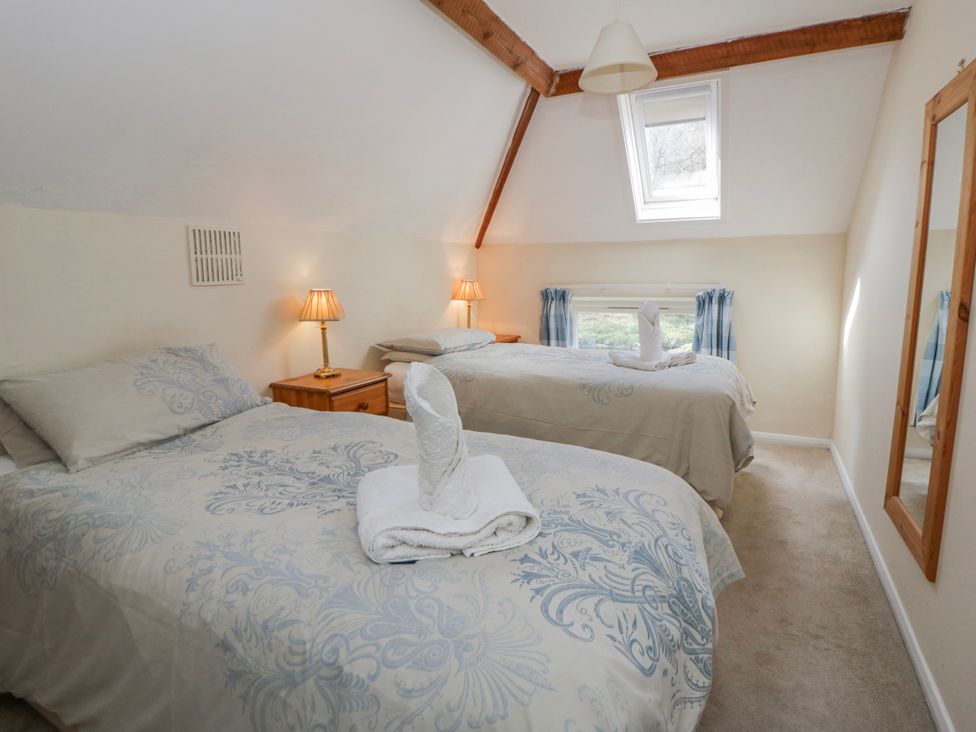 A bedroom with two beds and a mirror at Gardener's Cottage in Llanwrthwl near Rhayader