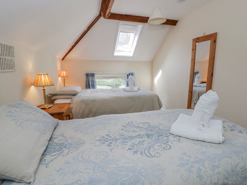 A bedroom with beds and a window at Gardener's Cottage in Llanwrthwl near Rhayader