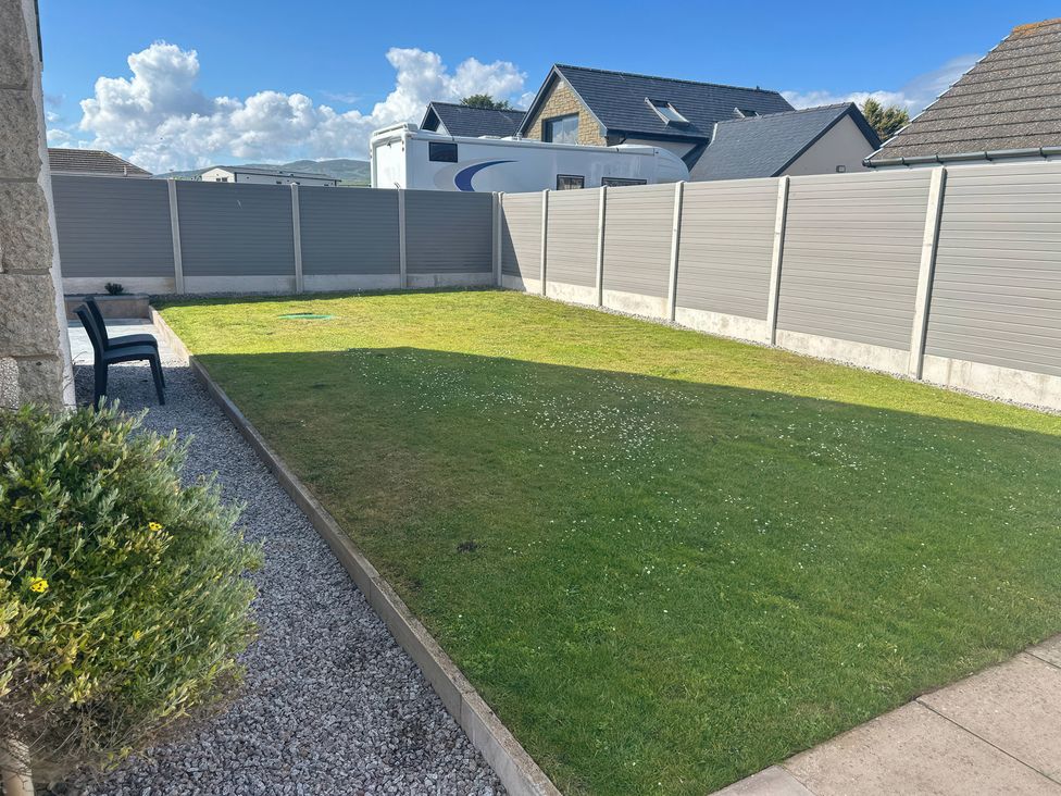 A garden with grass and a chair at The Bothy Southerness