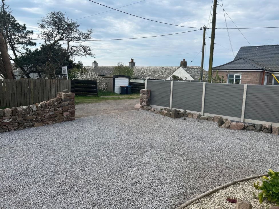 An outdoor area with a gravel driveway and a stone wall at The Bothy in Southerness