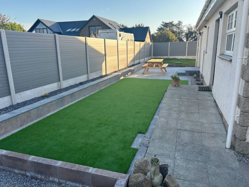 A garden with artificial grass and a picnic table at The Bothy in Southerness