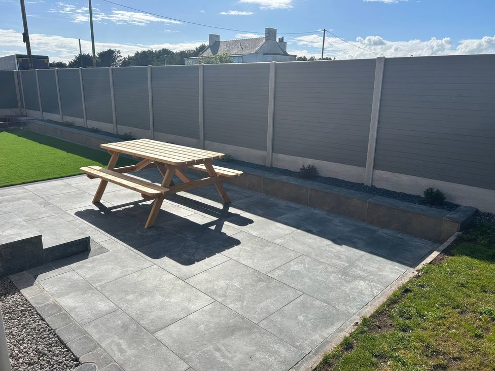 A garden with a wooden picnic table and grass at The Bothy in Southerness