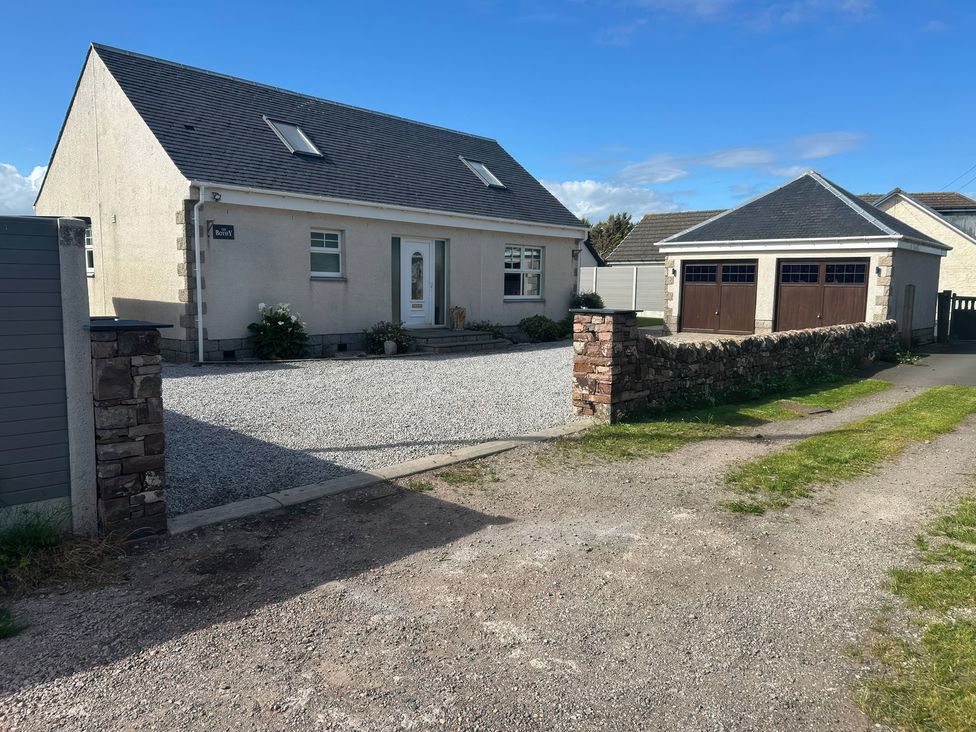 A house with a garage and gravel driveway at The Bothy in Southerness