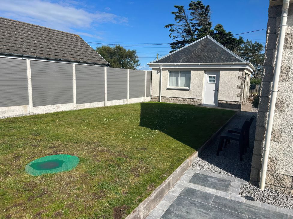 A garden with a house and chair at The Bothy in Southerness