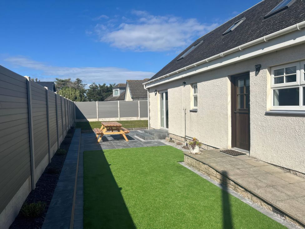 A garden featuring a lawn, patio, and seating area at The Bothy in Southerness