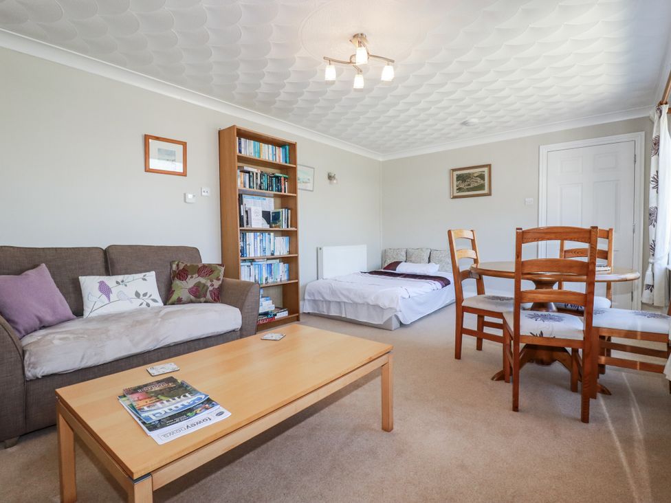 A living room with a sofa, coffee table, and dining table at Jenny Wren in Tywardreath near Fowey