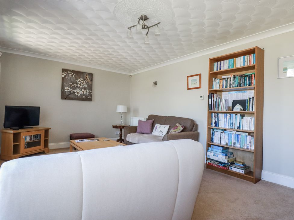 A living room with a television and bookshelves at Jenny Wren in Tywardreath near Fowey
