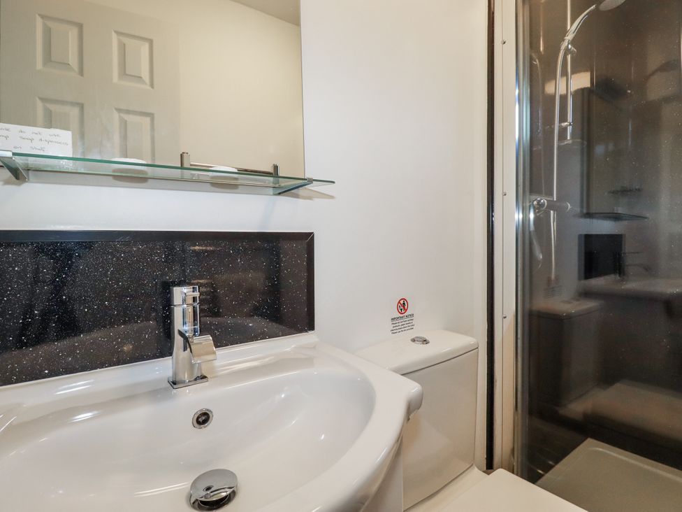 A bathroom with a sink, toilet, and shower at Jenny Wren in Tywardreath near Fowey
