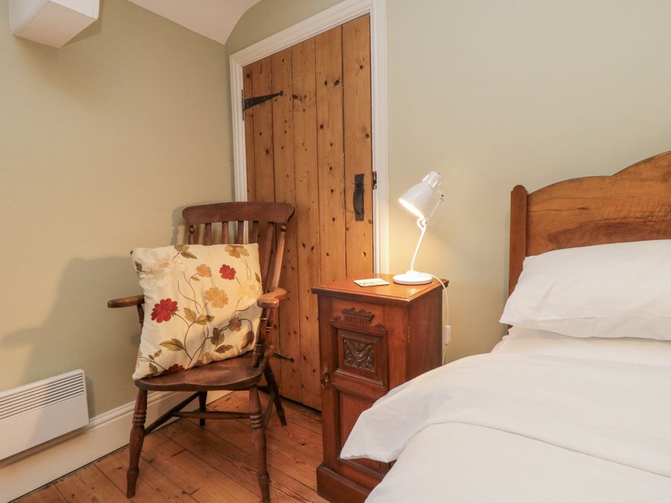 A bedroom with a bed, chair, lamp and door at Brookleigh Hutton-le-Hole