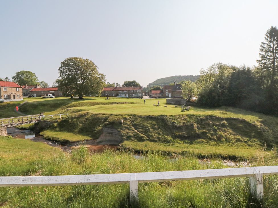 An outdoor area with houses and people walking dogs at Brookleigh in Hutton-le-Hole