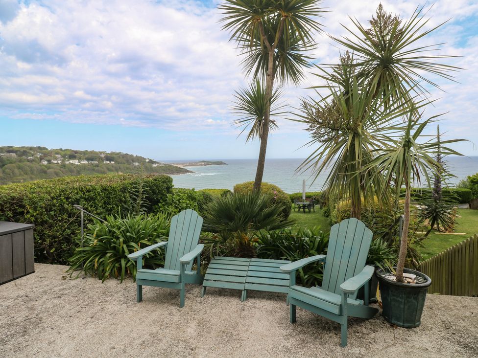 A patio with deck chairs and plants overlooking the ocean at Apartment 1 Llewellan St Ives