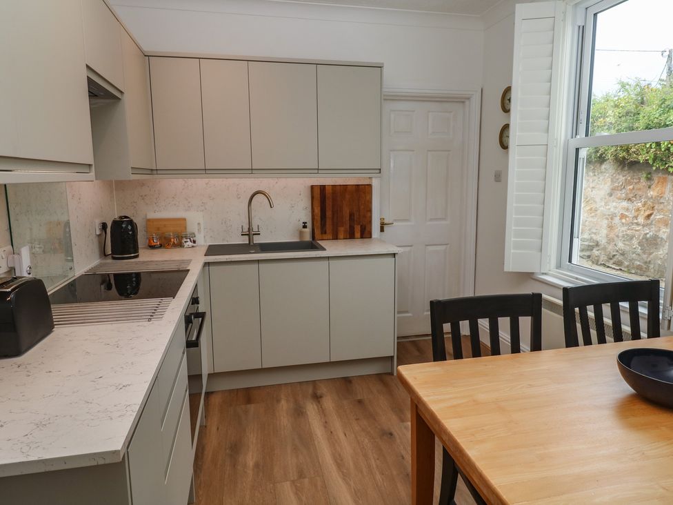 A kitchen with cabinets and a dining table at Apartment 1 Llewellan St Ives
