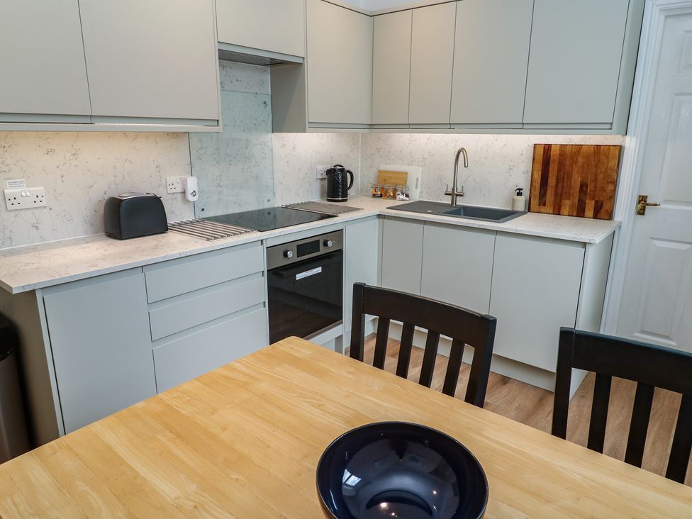 A kitchen with appliances and a table at Apartment 1 Llewellan St Ives