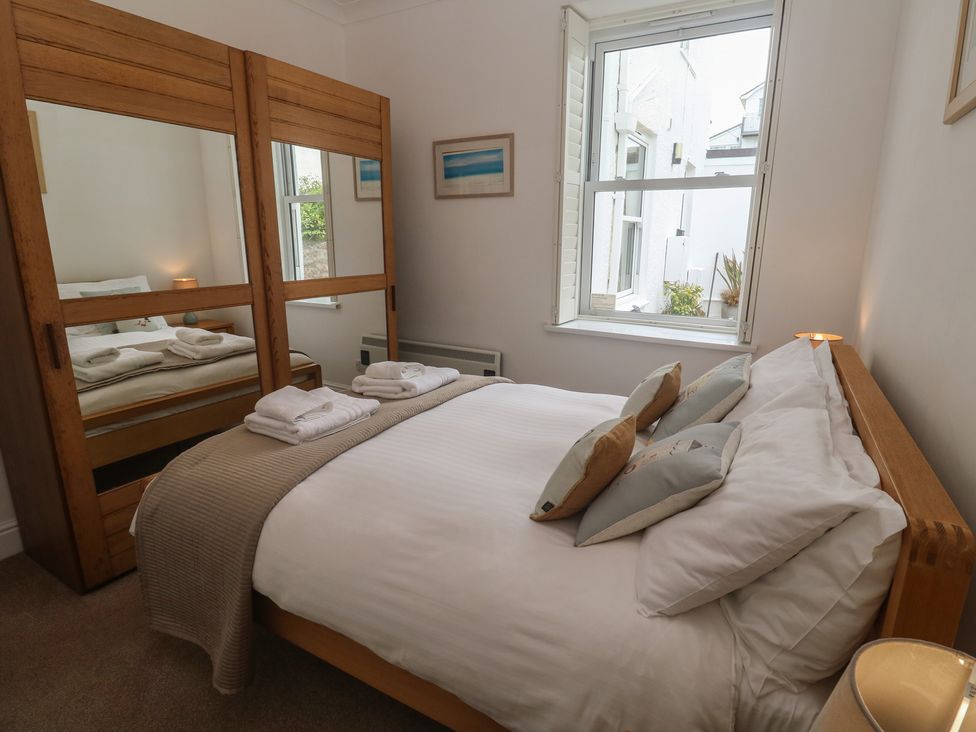 A bedroom with a bed and mirror at Apartment 1 Llewellan St Ives