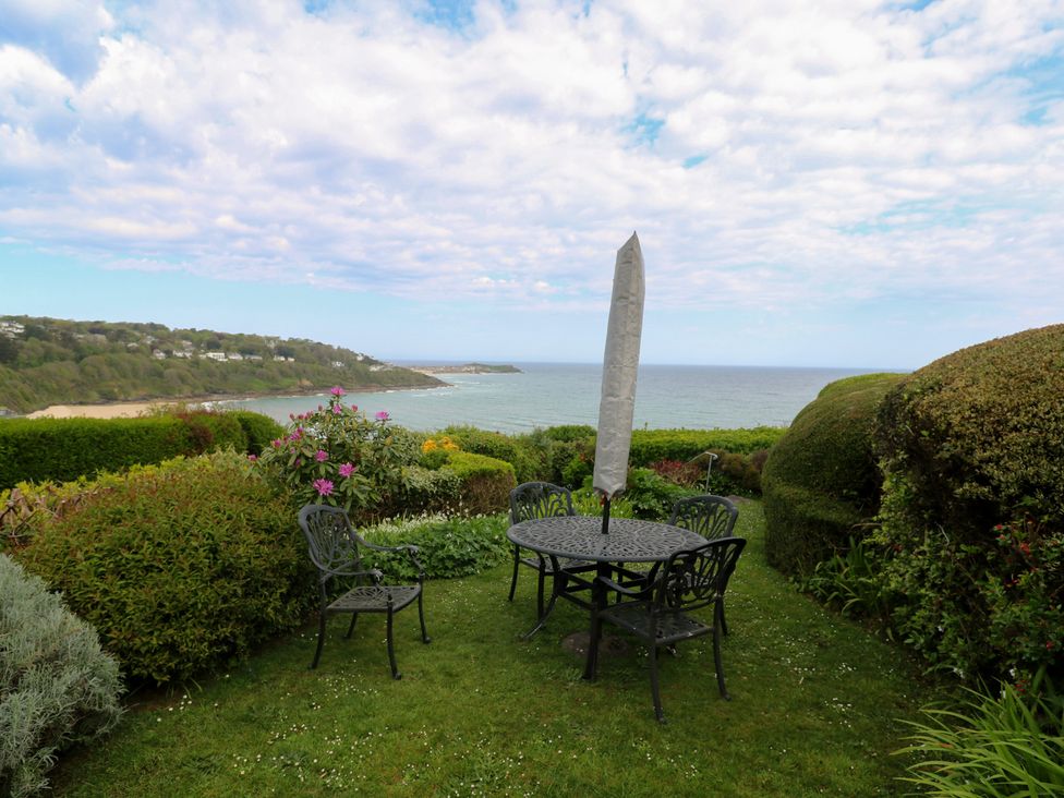 A garden with a table and chairs overlooking the sea at Apartment 1 Llewellan in St Ives