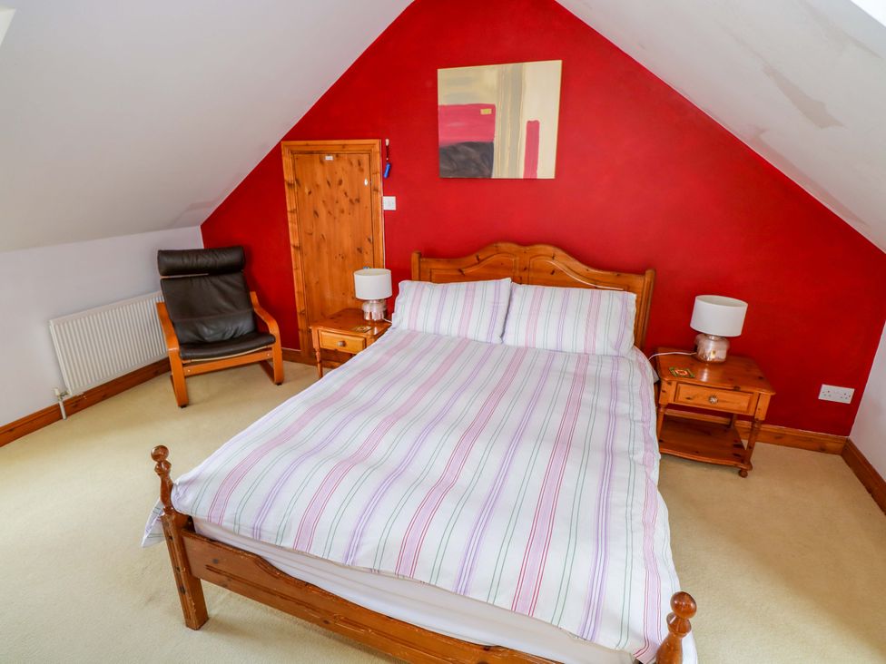 A bedroom with a bed beside tables and armchair at Ballaghboy Cottage Boyle, County Sligo