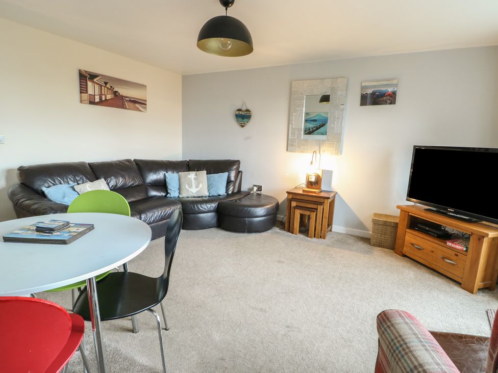 A living room with a sofa and TV at Beach View in Benllech near Red Wharf Bay