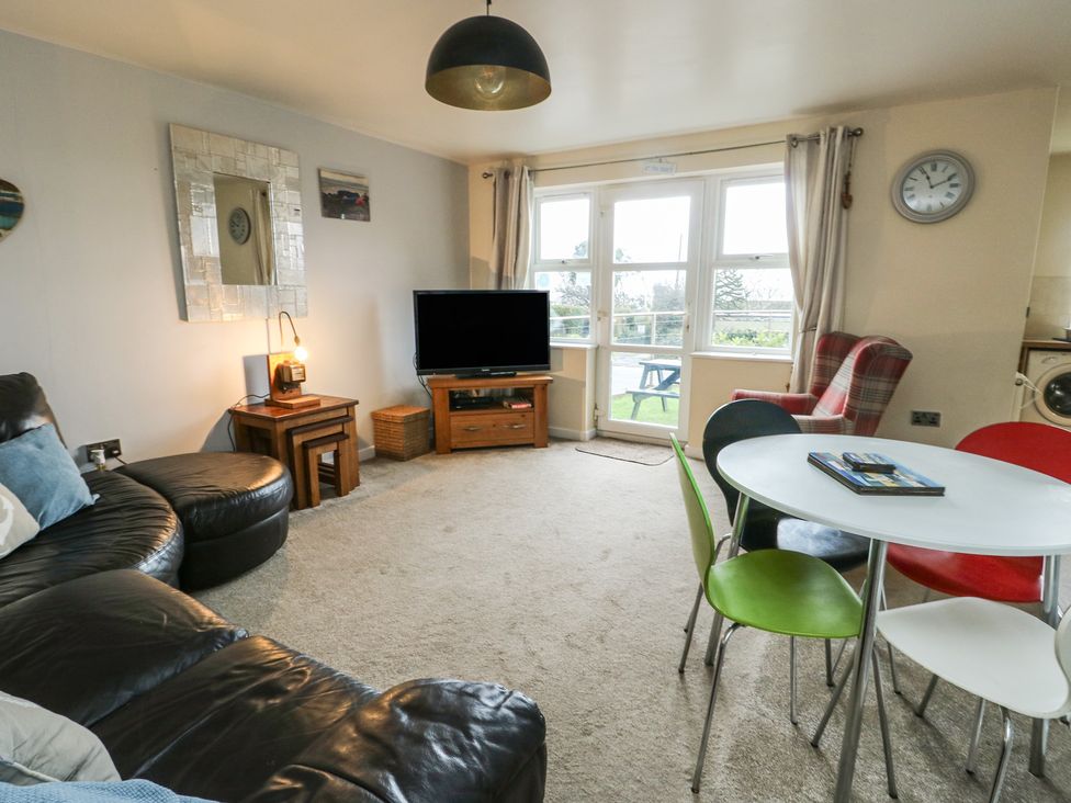 A living room with a television and dining table at Beach View in Benllech near Red Wharf Bay