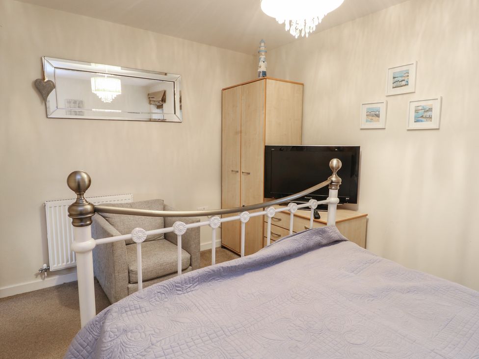 A bedroom with a bed, wardrobe, television and chair at Beach View in Benllech near Red Wharf Bay