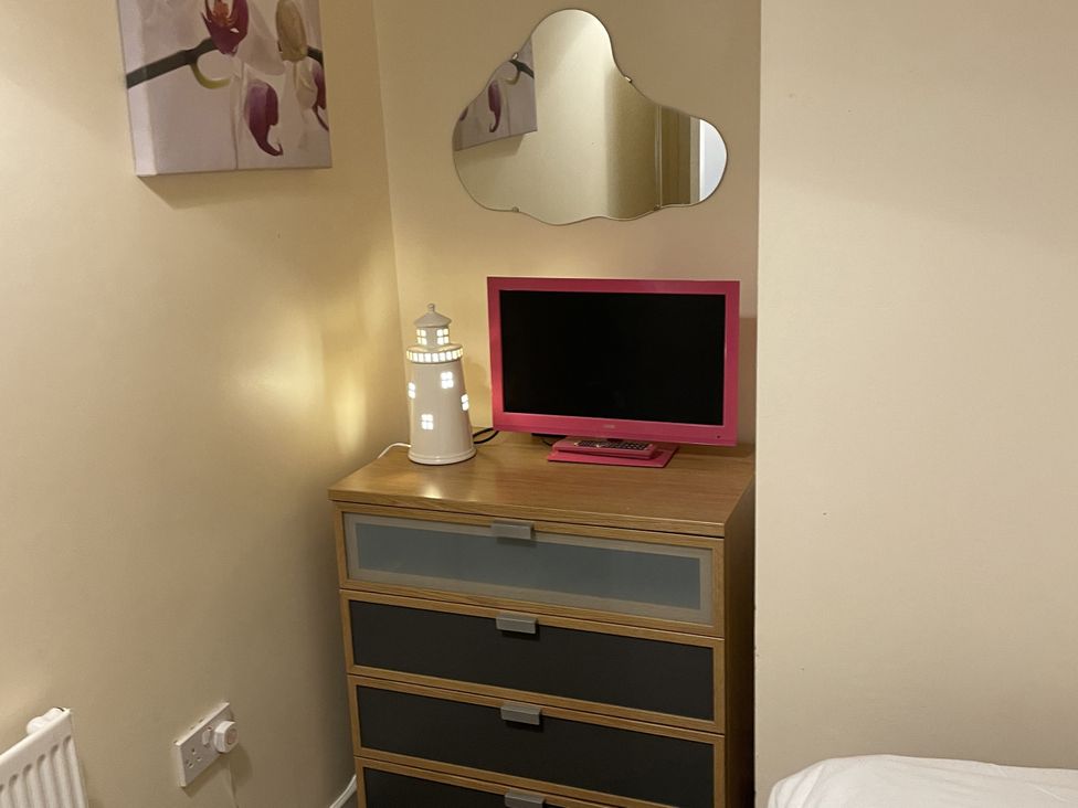 A bedroom with a dresser and television at Beach View Benllech near Red Wharf Bay