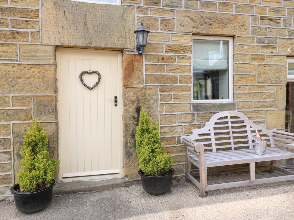An outdoor area with a door, bench, and planters at Bullace Barn Millhouse Green
