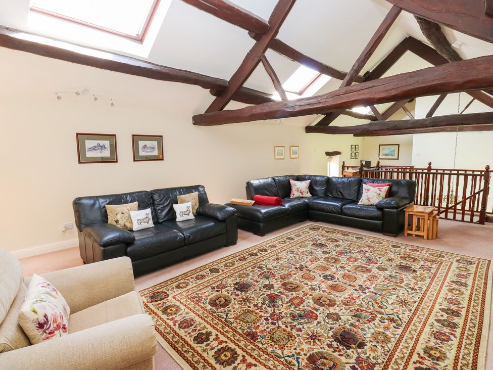 A living room with black sofas and a rug at Bullace Barn in Millhouse Green