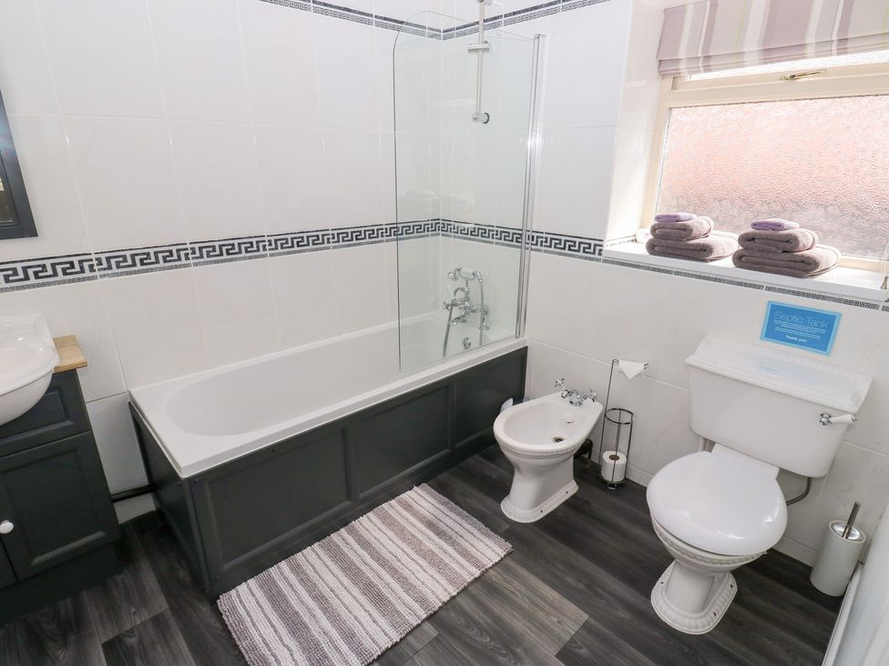 A bathroom with a bathtub, toilet, and sink at Bullace Barn Millhouse Green