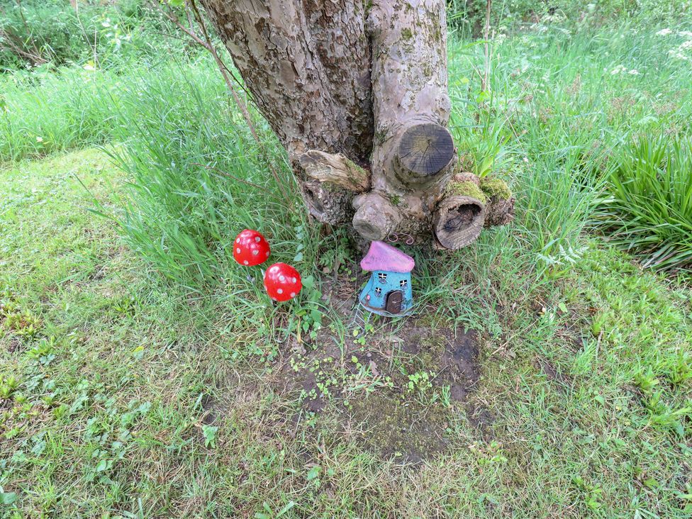 A fairy house and mushrooms at the base of a tree in a garden at Bullace Barn, Millhouse Green