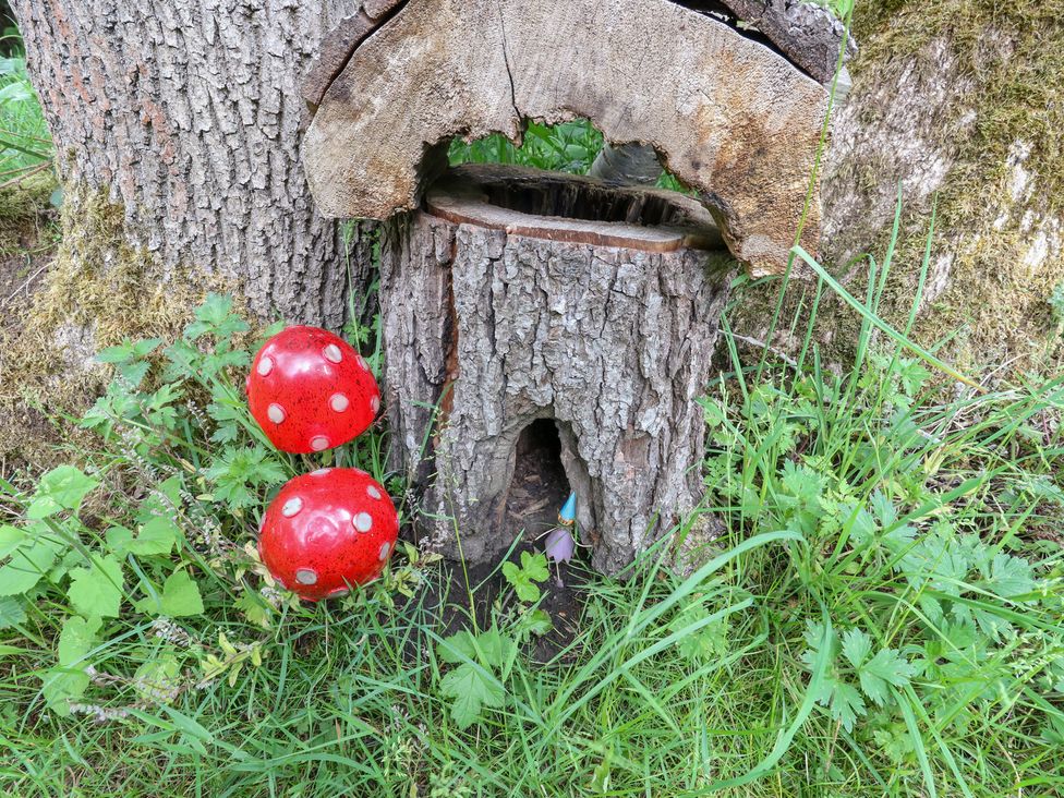 A tree stump with a small entrance and decorative mushrooms at Bullace Barn Millhouse Green
